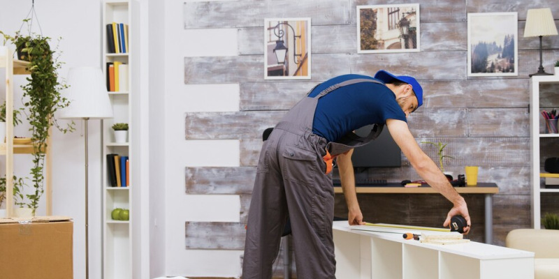 A builder measuring a shelf for a room/ home remodel.